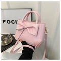 Close-up of pink bow handbag featuring premium leather texture and elegant metal zipper - Pink
