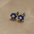Detail of flower-shaped blue zircon earrings with secure screw back on gold fabric - Silver-Dark Blue