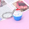 Close-up of cute 3D resin cupcake keychain with white cream and a tiny red heart - Blue