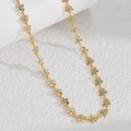 Detailed close-up of golden floral bracelet with blue stone accents on white background - Blue Flower Necklace
