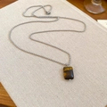 Detailed view of rectangle tiger eye stone pendant and silver bead chain on textile surface - Necklace-Silver-Coffee