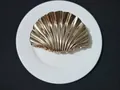 Top view of a gold-plated seashell hair claw clip with metallic texture on white plate - Large / Gold