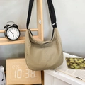 Bolso bandolera de media luna caqui minimalista con correa negra en un entorno de estilo de vida - Caqui