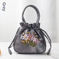 Grey satin drawstring handbag featuring detailed floral embroidery and a sleek finish - Gray
