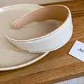 Detail of white pleated leather headband with fine edge stitching on wooden surface - White