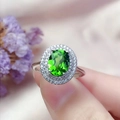 Silver ring featuring an oval green gemstone and diamond halo shown on a finger - White Gold [emerald] Ljz-274 / Adjustable Open