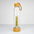 Close-up of glass energy bottle with yellow crystal pillar, gravel and bamboo lid - Yellow