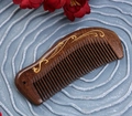 Sandalwood massage comb with gold curve engraving on dark brown wood surface - Gold Sandalwood Gilded Peacock