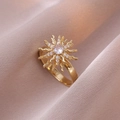 Close-up of a gold sunburst ring with a crystal center on soft pink silk fabric - Rotating Sunflower Ring (J0337) / Gold