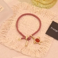 Dettaglio del bracciale rosa intrecciato con ciondolo tartaruga dorata e gemma rossa - Agata Rossa