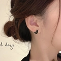 Elegantes pendientes de corazón en esmalte negro con borde dorado lucidos por modelo - Pendientes de botón de esmalte de corazón de oro negro