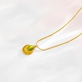 Detailed view of a gold snake chain necklace with a shell texture green stone pendant - Green