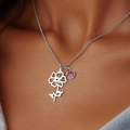 Silver flower pendant necklace with a pink birthstone worn by a female model - October