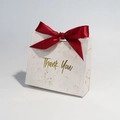 Detailed view of marble pattern gift bag with a red ribbon bow and gold Thank You text - Burgundy