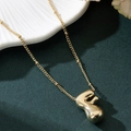 Macro shot of polished gold balloon letter F pendant on a delicate chain necklace - Letter F