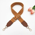 Close-up of orange-brown woven bag strap with golden buckles and geometric pattern - Yellow Brown with Brown Leather