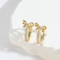 Exquisite Gold-Schleifenohrringe mit Zirkon-Pavé auf weißer strukturierter Steinfläche - Schleife