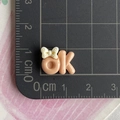 Detailed view of mini 1.5cm resin OK sign craft charm with a beige bow on a scale mat - Beige Coffee Mini - Bowtie OK