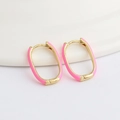 Detailed view of pink enamel and gold-plated oval hoop earrings on a white stand - Pink