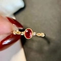 Nahaufnahme eines Goldrings mit ovalem rotem Edelstein und zartem Spitzenrand - Einstellbar Offen / Roter Hauptstein