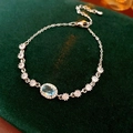 Gros plan d'un bracelet en argent avec pierre bleu clair ovale et zircons sur velours vert - Argent