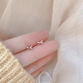 Close-up of minimalist silver X-shaped earrings held on fingertips with soft background - Small X Shape / Silver