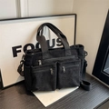 Black corduroy shoulder bag with multi-pocket design on dark wood surface - Black
