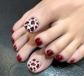 Dettaglio di unghie finte rosse per piedi con motivo leopardato sull'alluce - FW111