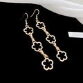 Dettaglio di orecchini a goccia a trifoglio dorati con tre fiori cavi su sfondo di seta bianca - Orecchini a Gancio - Oro - Fiore