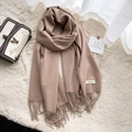 Soft khaki cashmere-feel scarf with Aesthetic label and tassels on white plush background - Camel