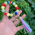 Close-up of colorful silicone beaded bracelet with blue leather tassel and gold clasp - Colorful