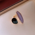 Detail of adjustable gold ring with oval purple and round black stones on satin - Purple