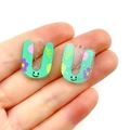 Close-up of mint green U-shaped acrylic charms with cartoon smiley faces and glitter - Letter U