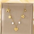 Dettaglio della collana dorata con ciondoli a fiocco, perla e cuore su seta - Stile Fiocco e Margherita con Perla (KN292155-SXSJ)