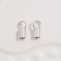 Close-up of S925 sterling silver cord end caps with loops for jewelry making and beading - Medium 2.5mm / White Gold