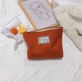 Detail of orange houndstooth canvas pouch with Time to Party tag on cozy bed - Solid Orange Red