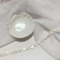 Detail view of drop-shaped mother of pearl beads on a white ceramic shell plate - 10*15 Teardrop