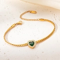 Detailed macro view of a golden stainless steel bracelet with a green heart emerald stone - Heart Emerald Bracelet