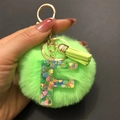 Detail of resin letter F keychain with lime green pompom, tassel and gold metal hardware - Letter F