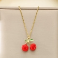 Detailed close-up of a gold cherry pendant necklace with red enamel on a jewelry stand - Two Red Cherries With Green Leaf Style (KN292074-Z)