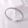 Detail of silver twisted woven metal mesh cuff bracelet on minimalist white display stand - Steel 3