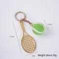 Miniature tennis keychain with a gold racket and green fuzzy ball on white background - 2.5cm Large Dark Green Tennis Ball + Gold Racket