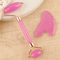 Detailed view of pink resin facial roller and heart-shaped gua sha set on a stone stand - Resin Roller Transparent Pink