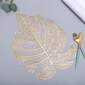 Detail shot of golden PVC monstera leaf placemat with hollow design on dining table - 38cm / Gold