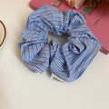 Vista dettagliata di un elastico per capelli a righe blu e bianche con etichetta - Strisce blu scuro