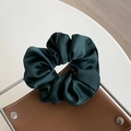Deep green satin silk scrunchie with rich texture shown on an elegant jewelry display - Green