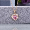 Detalle macro del collar de circón rosa en forma de corazón con cadena dorada y engaste halo - Tono Dorado