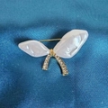 Macro detail of a golden bow brooch with white resin wings and sparkling rhinestones - Shell Butterfly Brooch