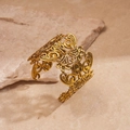 Detailansicht eines vintage Goldarmreifs mit hohlem Spitzenmuster auf Steinbasis - Gold