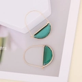 Chic gold-framed emerald green glass crescent earrings displayed on geometric props - Green